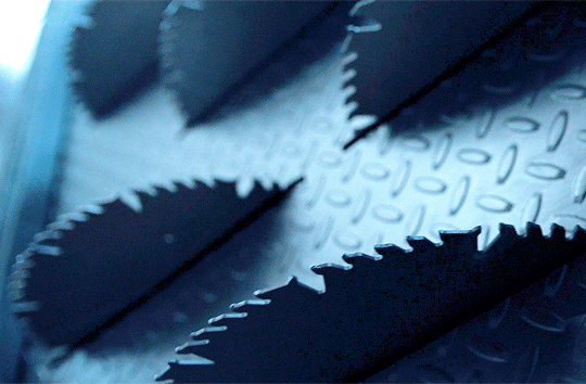 Spinning saw blades on a vertical metal wall